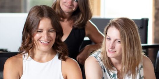 Photo of three people working together around a computer