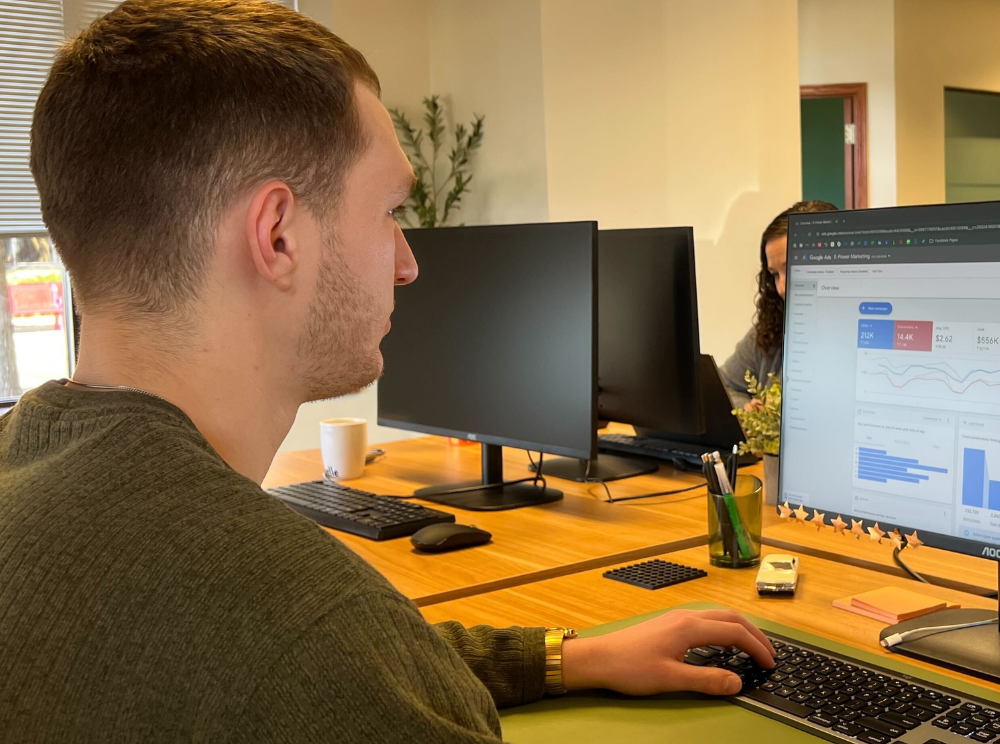Photo of a man working in an office setting and reviewing metrics on a screen